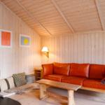 Living room with wooden walls, red sofa, stove, and wooden table.
