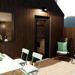 Terrace with table, chairs, and loungers. Background: wooden wall and view of field.