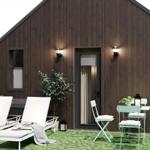 Modern wooden cabin with outdoor terrace, loungers, and table with chairs.