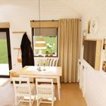Dining room with table, chairs, and window. Kitchen and TV wall visible.