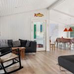 Wohn- und Essbereich mit schwarzen Sofas, Holzboden und weißem Paneelwandverkleidung.