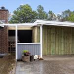 Haus mit Terrasse, Holzwand und Grillbereich im Freien.