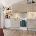Küche mit Holzschrank, Spüle, Herd und Backofen. Durchgang zum Garten mit Holzterrasse.