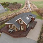 Modern house with terrace and garden. River and fields in the background.