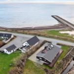 House with terrace by the coast, view of water and beach.