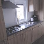 Küche mit Holzschränken, Herd, Spüle und Fenster.