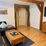 Wohnzimmer mit Sofa, Couchtisch und Fernseher. Holzbalken und Parkettboden.