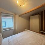 Schlafzimmer mit Bett, Fenster, Kleiderschrank und Holzbalken an der Decke.