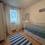 Schlafzimmer mit Bett, Schrank und Fenster mit Vorhängen.