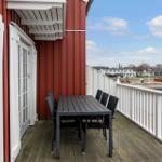 Deck with table and chairs, view of water and harbor basin.