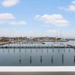 View of harbor with boats and houses under blue sky