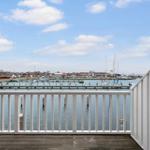 View of harbor with boats and red houses from balcony.