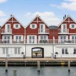 Red houses with white balconies stand by the water.