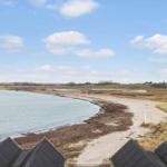 View of a beach with marshland and green hills under a blue sky.