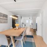 Dining room with wooden table, chairs, and view into the kitchen.