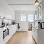 Kitchen with white cabinets, wooden floor, and view of balcony.