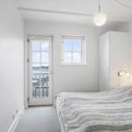 Bedroom with bed, windows, and door to balcony with water view.