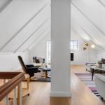 Attic apartment with wooden floor, seating areas, and windows.
