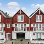 Red wooden houses with white balconies and window frames under blue sky.