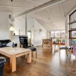 Living and dining area with hardwood floors, black leather furniture, and large windows.