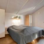 Bedroom with bed, wardrobes, and window. Wooden floor and white walls.