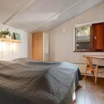 Bedroom with bed, desk, and window. Wooden walls and floor.