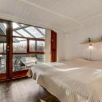 Bedroom with large bed, wooden floor, and floor-to-ceiling windows to terrace.