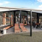 Terrace with lounge chairs and table. Outdoor area with sink and wooden wall.