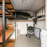 Vaulted room with shelves, grill, washing machine, and wood for fireplace.