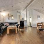 Living and dining area with wooden floor, black leather furniture, and dining table.