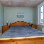Schlafzimmer mit Holzbett, Nachttischen und Fenster mit Blick auf Landschaft.