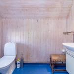 Badezimmer mit Holzwand, Toilette, Waschbecken und Fenster.