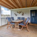Terrasse mit Holztisch, sechs Stühlen und Hirschgeweih an der Wand.