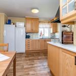 Küche mit Holzmöbeln, Kühlschrank, Spüle und Esstisch.