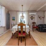 Esszimmer mit Esstisch, Stühlen und Wohnbereich mit Sofa und Wanddekoration.
