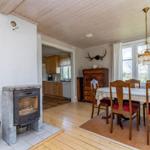 Esszimmer mit Holztisch, Stühlen und Kamin. Küche im Hintergrund.