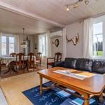 Wohn- und Essbereich mit Sofa, Esstisch und Holzboden. Fenster mit Blick auf Grünfläche.