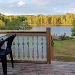 Terrasse mit Tisch, Stühlen und Blick auf einen See.