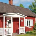 Rotes Haus mit weißem Vordach, Blumenkästen und Holzbank im Garten.