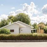 Moderne Villa mit Garten, Terrasse und Sonnenschirm. Umgeben von Bäumen und Sträuchern.