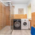 Dusche mit Glaswand, Waschmaschine und Trockner in modernem Badezimmer.