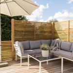 Terrasse mit Sitzgruppe, Sonnenschirm und Holzgeländer.