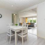 Esszimmer mit Tisch und Stühlen. Durchgang zum Wohnzimmer mit Sofa und Fenstern.