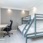 Zimmer mit Doppelstockbett und Schreibtisch mit Stuhl.