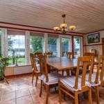 Esszimmer mit Holztisch, Stühlen und Fenstern zum See