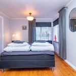 Schlafzimmer mit Bett, Fenster und Holzboden. An der Wand hängt ein Spiegel.