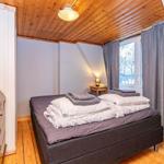 Schlafzimmer mit Bett, Holzdecke und Fenster mit Vorhängen.