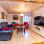 Wohnzimmer mit Sofa, Sesseln, TV und Holzboden.