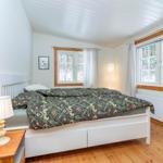Schlafzimmer mit Bett, Fenstern und Holzboden.