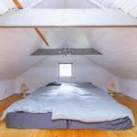 Schlafzimmer mit Dachschrägen, Holzboden und Bett unter Dach